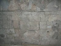 Part del mur medieval, que es pot veure per sobre de la volta de la nau lateral de migdia, amb una finestre paredada